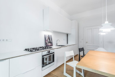 Einzeilige, Mittelgroße Moderne Wohnküche ohne Insel mit Doppelwaschbecken, flächenbündigen Schrankfronten, weißen Schränken, Arbeitsplatte aus Holz, Küchenrückwand in Weiß, Küchengeräten aus Edelstahl, hellem Holzboden, braunem Boden und weißer Arbeitsplatte in Frankfurt am Main