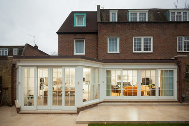 Photo of a large three-storey brick red duplex exterior in London with a gambrel roof and a tile roof.