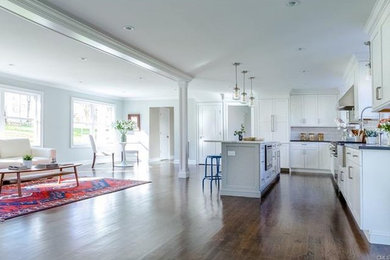 Large transitional l-shaped dark wood floor open concept kitchen photo in New York with a farmhouse sink, shaker cabinets, white cabinets, quartz countertops, white backsplash, subway tile backsplash, stainless steel appliances and an island