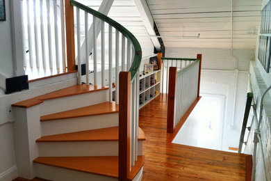 Staircase - mid-sized coastal wooden curved wood railing staircase idea in Providence with painted risers