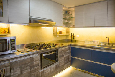 Example of a small trendy l-shaped ceramic tile and gray floor kitchen pantry design in Other with an integrated sink, flat-panel cabinets, blue cabinets, stainless steel countertops, yellow backsplash, stone tile backsplash, stainless steel appliances and an island