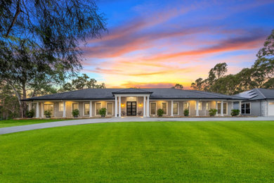 Large country one-storey concrete grey house exterior in Sydney with a hip roof, a shingle roof and a grey roof.