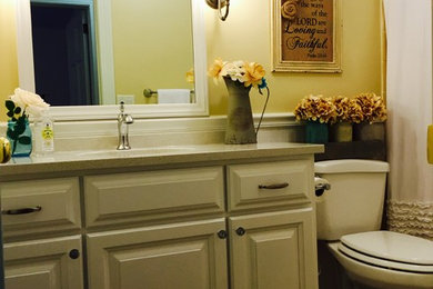 Tub/shower combo - mid-sized farmhouse brown tile and ceramic tile ceramic tile tub/shower combo idea in Charleston with an undermount sink, raised-panel cabinets, white cabinets, quartzite countertops and yellow walls