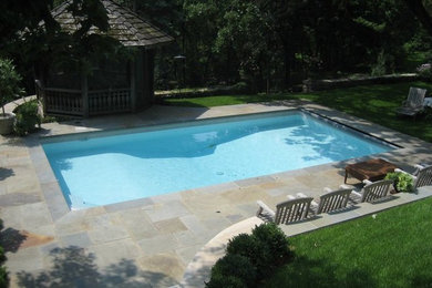 Photo of a large traditional backyard rectangular lap pool in Minneapolis with a pool house and stamped concrete.