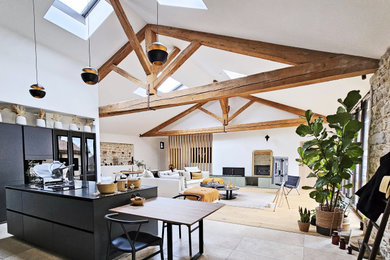 Cette photo montre une grande salle de séjour tendance ouverte avec un mur blanc, parquet clair, une cheminée ribbon, un manteau de cheminée en pierre, un téléviseur indépendant, un sol beige, poutres apparentes et éclairage.