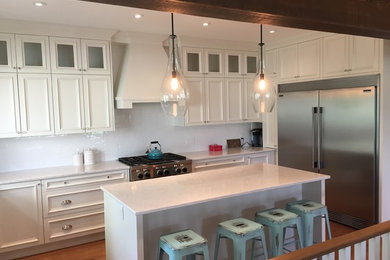 Inspiration for a mid-sized transitional u-shaped medium tone wood floor eat-in kitchen remodel in Calgary with recessed-panel cabinets, white cabinets, marble countertops, white backsplash, porcelain backsplash, stainless steel appliances and an island