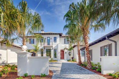 Large island style white two-story stucco gable roof photo in Tampa