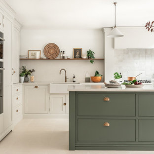 Große Klassische Wohnküche in L-Form mit Landhausspüle, Schrankfronten im Shaker-Stil, grünen Schränken, Quarzit-Arbeitsplatte, Küchenrückwand in Weiß, Rückwand aus Steinfliesen, schwarzen Elektrogeräten, Keramikboden, Kücheninsel, beigem Boden und weißer Arbeitsplatte in Surrey