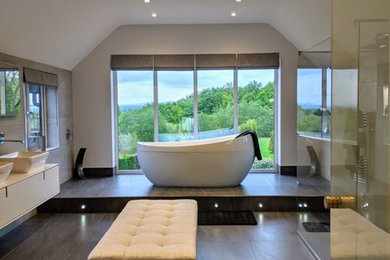 Large modern ensuite bathroom in Cheshire with white cabinets, a freestanding bath, a walk-in shower, grey tiles, porcelain tiles, grey walls, porcelain flooring, grey floors, an open shower and white worktops.