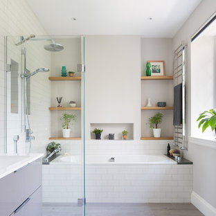 Cette image montre une salle de bain design de taille moyenne avec un placard à porte plane, une baignoire posée, un espace douche bain, un carrelage blanc, un carrelage métro, un mur gris, sol en stratifié, un lavabo suspendu, un sol gris et aucune cabine.