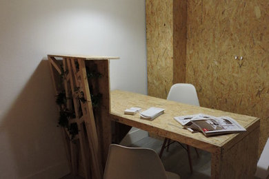Diseño de estudio minimalista pequeño con paredes blancas, suelo de madera clara, escritorio independiente y suelo azul