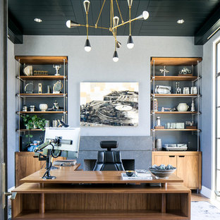 This is an example of a contemporary study room in Orange County with grey walls, carpet, a standard fireplace, a stone fireplace surround, a freestanding desk and purple floor.