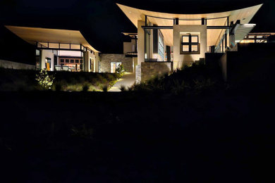 Immagine della villa grande beige moderna a due piani con rivestimenti misti, copertura in metallo o lamiera e tetto grigio