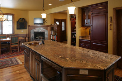 Eat-in kitchen - mid-sized traditional l-shaped medium tone wood floor eat-in kitchen idea in Other with an undermount sink, raised-panel cabinets, dark wood cabinets, granite countertops, stainless steel appliances and an island