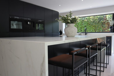 Inspiration for a large modern l-shaped open plan kitchen in Hampshire with a single-bowl sink, engineered stone countertops, black appliances, ceramic flooring, an island, white floors and white worktops.