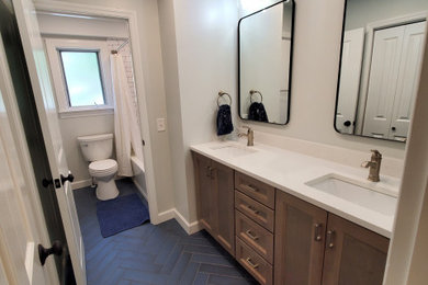 Mid-sized transitional kids' ceramic tile, blue floor and double-sink tub/shower combo photo in Cincinnati with shaker cabinets, medium tone wood cabinets, quartz countertops, white countertops and a built-in vanity