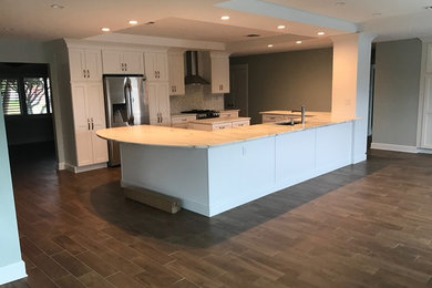 Inspiration for a large transitional galley open plan kitchen in Tampa with an undermount sink, shaker cabinets, white cabinets, marble benchtops, multi-coloured splashback, mosaic tile splashback, stainless steel appliances, porcelain floors, multiple islands and brown floor.