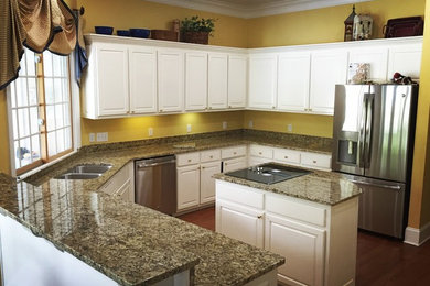Mid-sized elegant u-shaped medium tone wood floor and brown floor kitchen photo in Nashville with an undermount sink, raised-panel cabinets, white cabinets, granite countertops, stainless steel appliances and an island