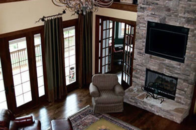 Example of a large transitional open concept dark wood floor family room design in Other with yellow walls, a standard fireplace, a stone fireplace and a media wall