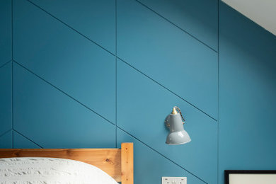 Photo of a small retro guest bedroom in London with blue walls, carpet, beige floors and panelled walls.