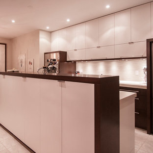 Idée de décoration pour une arrière-cuisine parallèle minimaliste de taille moyenne avec un évier 2 bacs, un placard à porte plane, des portes de placard blanches, un plan de travail en granite, une crédence grise, un électroménager en acier inoxydable, un sol en carrelage de céramique et un îlot central.