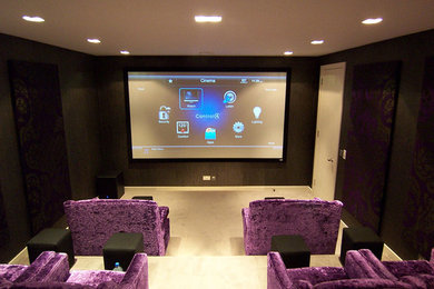 На фото: большой изолированный домашний кинотеатр в стиле модернизм с черными стенами, ковровым покрытием и проектором с