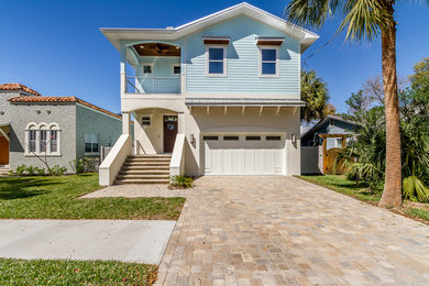 This is an example of a large beach style two-storey blue exterior in Tampa with vinyl siding and a flat roof.