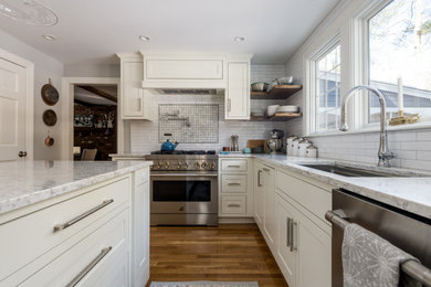 Inspiration for a transitional l-shaped light wood floor kitchen remodel in Boston with recessed-panel cabinets, white cabinets, ceramic backsplash, stainless steel appliances and an island
