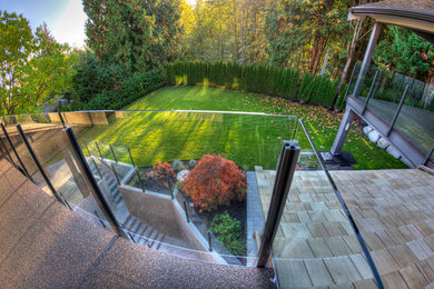 This is an example of a large contemporary backyard patio in Vancouver with natural stone pavers and a roof extension.