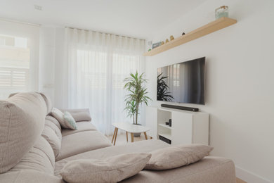 Diseño de salón abierto nórdico de tamaño medio sin chimenea con paredes blancas, suelo de madera en tonos medios, televisor colgado en la pared y suelo marrón
