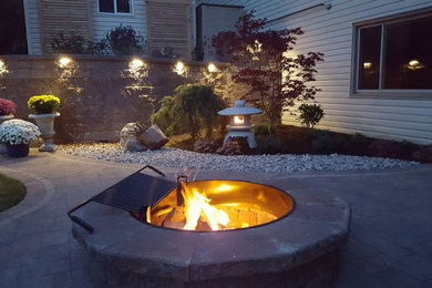 Traditional backyard patio in Other with a fire feature and brick pavers.