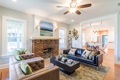 This is an example of a mid-sized arts and crafts open concept living room in Jacksonville with grey walls, light hardwood floors, a standard fireplace and a brick fireplace surround.
