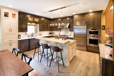 Example of a large transitional u-shaped ceramic tile and brown floor eat-in kitchen design with a single-bowl sink, flat-panel cabinets, medium tone wood cabinets, quartz countertops, beige backsplash, quartz backsplash, stainless steel appliances, an island and beige countertops