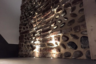 La parete in mattoni e sassi recuperata e valorizzata con luci a Led a pavimento