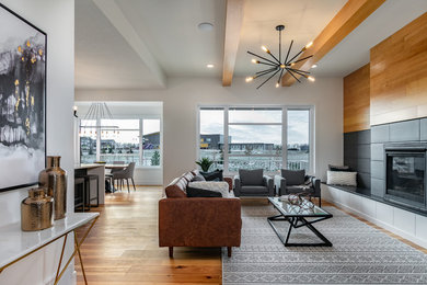 Living room - large contemporary open concept light wood floor and brown floor living room idea in Edmonton with white walls, a standard fireplace, a wood fireplace surround and a wall-mounted tv