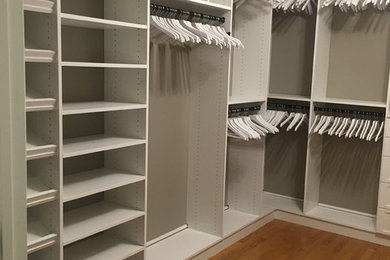 Modelo de armario vestidor unisex clásico grande con puertas de armario blancas y suelo de madera en tonos medios