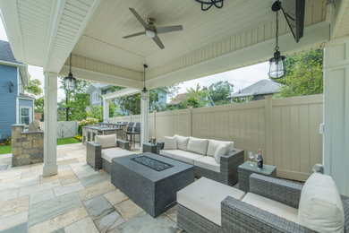 Example of a large transitional backyard stone patio kitchen design in New York with a gazebo