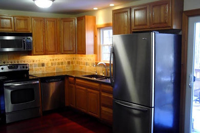 Inspiration for a mid-sized timeless u-shaped medium tone wood floor kitchen remodel in Providence with a double-bowl sink, raised-panel cabinets, light wood cabinets, quartzite countertops, multicolored backsplash, ceramic backsplash and stainless steel appliances
