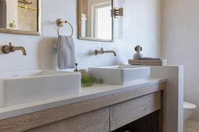 Example of a mid-sized tuscan master beige tile and ceramic tile mosaic tile floor, beige floor and double-sink bathroom design in San Francisco with flat-panel cabinets, distressed cabinets, a one-piece toilet, beige walls, a vessel sink, quartz countertops, white countertops, a niche and a built-in vanity