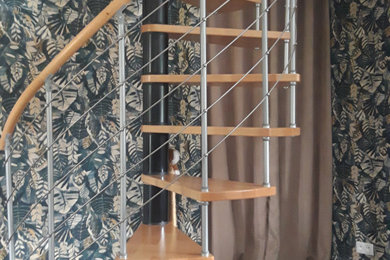 Inspiration pour un escalier sans contremarche hélicoïdal traditionnel avec des marches en bois, un garde-corps en câble et du papier peint.