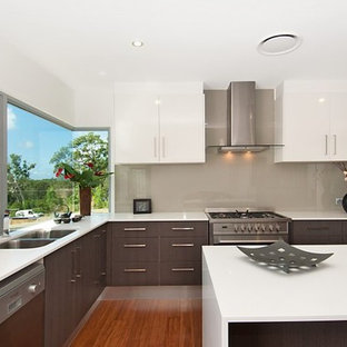 Mid-sized contemporary kitchen pantry ideas - Mid-sized trendy l-shaped bamboo floor kitchen pantry photo in Sunshine Coast with a double-bowl sink, flat-panel cabinets, dark wood cabinets, solid surface countertops, beige backsplash, glass sheet backsplash, stainless steel appliances and an island