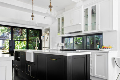 Galley kitchen in Sydney with a farmhouse sink, shaker cabinets, black appliances, with island and black floor.