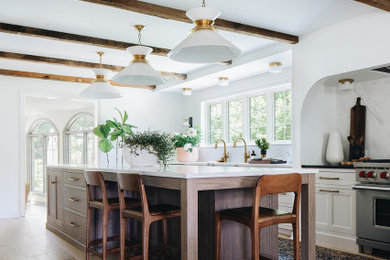 Example of a classic light wood floor, brown floor and exposed beam eat-in kitchen design in Grand Rapids with shaker cabinets, white cabinets, marble countertops, white backsplash, marble backsplash, stainless steel appliances, an island and white countertops