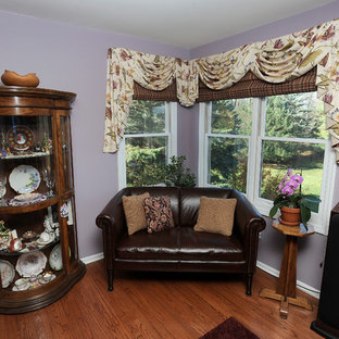 Foto de salón abierto, mediterráneo, grande, con paredes púrpuras, suelo de madera en tonos medios, chimenea tradicional, marco de chimenea de ladrillo y televisor colgado en la pared