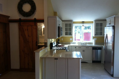 Example of a mid-sized l-shaped porcelain tile eat-in kitchen design in Boston with an undermount sink, flat-panel cabinets, white cabinets, granite countertops and stainless steel appliances