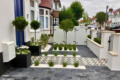 Inspiration for a small contemporary front driveway fully shaded garden in London with natural stone paving.