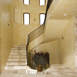 Mediterranean curved metal railing staircase in San Francisco with travertine treads and travertine risers.