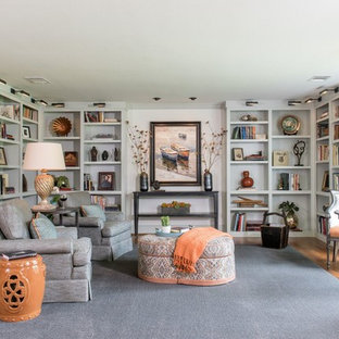Idée de décoration pour un salon avec une bibliothèque ou un coin lecture tradition de taille moyenne et fermé avec un mur blanc, un sol en bois brun, aucune cheminée et aucun téléviseur.