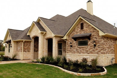 Large elegant beige one-story brick house exterior photo in Houston with a hip roof and a shingle roof