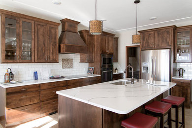 Example of a large classic l-shaped beige floor and ceramic tile kitchen design in Other with an undermount sink, shaker cabinets, dark wood cabinets, quartzite countertops, white backsplash, subway tile backsplash, stainless steel appliances and an island